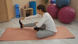 © Krakenimages.com - Woman stretching on pink mat in indoor gym setting with yoga and exercise equipment visible
