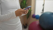 © Krakenimages.com - Woman texting in a gym interior, displaying her hands holding a smartphone with gym equipment in the background.
