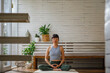 © Jovo Jovanovic/Stocksy - Active young female meditating in living room at home