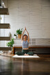 © Jovo Jovanovic/Stocksy - Active young woman practicing yoga at home