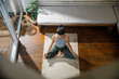 © Jovo Jovanovic/Stocksy - High angle view of young woman meditating at home