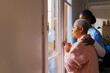 © BONNINSTUDIO/Stocksy - Caregiver comforting elderly woman looking out window