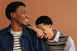© BONNINSTUDIO/Stocksy - Men laughing together in brown background