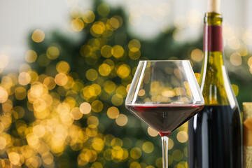 Canvas Print - Glass and bottle of red wine against blurred Christmas lights, closeup. Bokeh effect