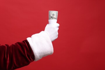 Wall Mural - Santa Claus with dollar banknotes on red background, closeup. Space for text