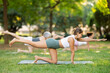 © JackF - Sporty energetic females doing exercises on pilates mat during group training in green park at daytime. Fitness concept