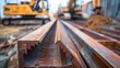 © aan - A steel L angle tube with a high carbon finish, placed on a construction site, with an industrial metalworking environment and machinery visible in the distance.
