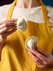 A woman presents two dumplings in her hands, presenting a traditional dish.