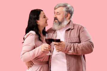 Wall Mural - Beautiful mature couple with glasses of wine on pink background. Valentine's Day celebration