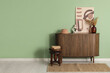 © Pixel-Shot - Chest of drawers with pampas grass, picture and books on stool near green wall in room