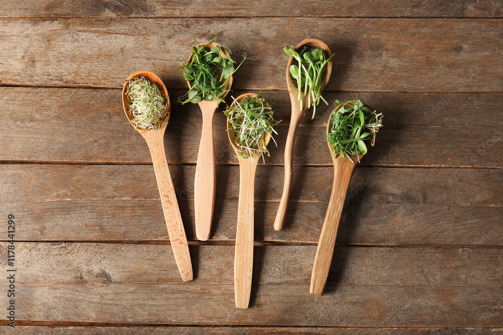 Spoons with different micro green on wooden background