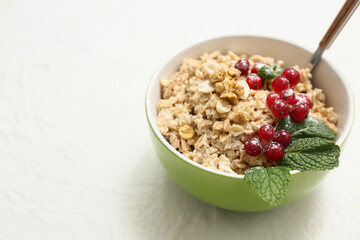 Wall Mural - Bowl with tasty oatmeal and cranberries on white background, closeup