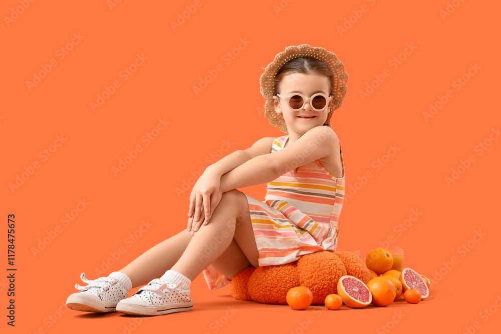 Cute little girl with citruses sitting on orange background