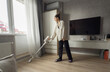 © Mihail - A woman cleans her living room using a wireless vacuum cleaner, ensuring a tidy space while dressed casually in a comfortable outfit