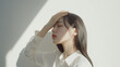 © dont - 光が差し込む部屋で頭を抑えて目を瞑っている　頭痛・体調が悪い女性の顔のクローズアップ　日本人　アジア人