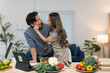 © crizzystudio - Happy asian couple is cooking healthy food together in their kitchen, they're hugging and laughing while preparing a meal with fresh vegetables