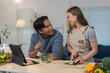 © crizzystudio - Young asian couple preparing a vegetable salad together in a modern kitchen, following a recipe on a tablet, promoting healthy lifestyle and sharing quality time