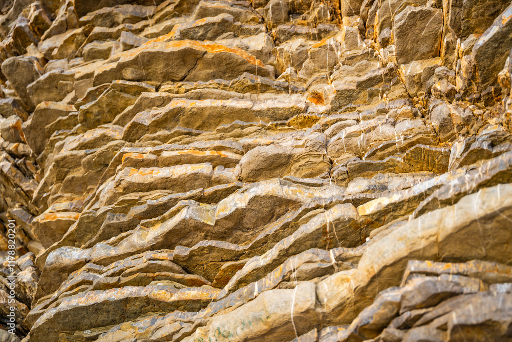 Layered rock texture in Budva, Montenegro. Sedimentary rocks with rugged surface of gray and ...