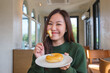 © Farknot Architect - Portrait image of a young asian woman holding and eating donut