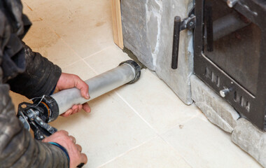 A man is using a caulking gun to seal a crack in a wall