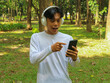 © Lailar Studio - Asian man relax in nature using mobile phone while listening music