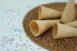 © PinkyEn - five empty ice cream cones lying on a rustic brown base with colorful sprinkles, isolated on white background