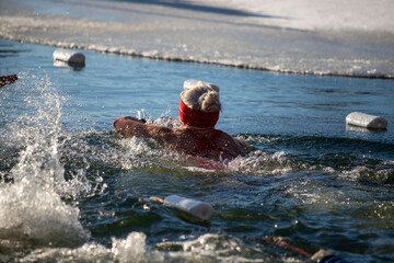 Wall Mural - A woman swims in a lake with a red hat on