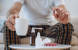 © standret - Table with cup and spray. Guy is sitting and taking a pills, feeling sick, bad