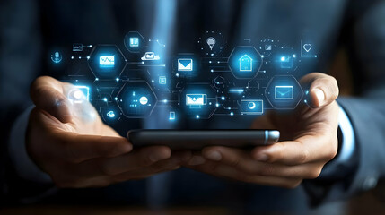 Businessman interacts with holographic app icons displayed above smartphone, managing digital tasks.