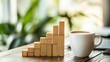 © KYR - A coffee cup beside a bar chart made of wooden blocks, symbolizing the growth and progress of a business in a sleek, modern workspace environment.