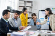 © Wasana - A group of people are gathered around a table with a white board and a laptop