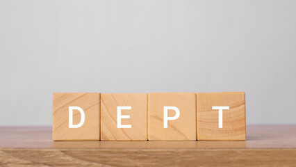 Dept word written on wooden blocks on a wooden table with a light gray background. Finance and department concept