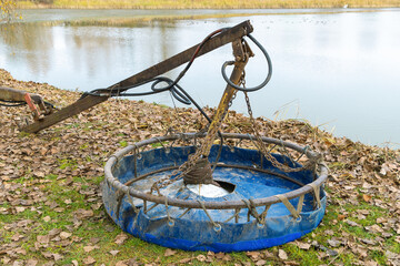 Close-up of a blue industrial dredging tool with chains, hoses, and metal frame