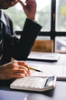 © Suphakant - Accountant working at desk using calculator to calculate company's annual financial and tax report. financial concept