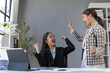 © amnaj - Two asian businesswomen are cheering with raised fists in a modern office, expressing their joy and excitement over a successful project