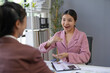 © amnaj - Asian businesswomen discussing marketing strategy using charts and graphs, explaining and gesturing at office meeting