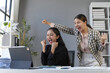 © amnaj - Two euphoric businesswomen screaming with joy while looking at a tablet in the office, celebrating a successful project or achievement