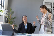 © amnaj - Two asian businesswomen are celebrating a successful project in their office, laughing and raising their fists in the air