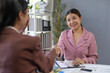 © amnaj - Two businesswomen shaking hands after closing a successful business deal in the office, celebrating their partnership