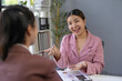 © amnaj - Two asian businesswomen discussing and explaining financial chart during a meeting in a modern office