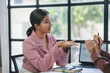 © amnaj - Two businesswomen engaging in a discussion about graphs while collaborating in an office setting, surrounded by laptops and notebooks