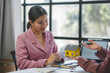 © amnaj - Real estate agent showing a scale model house to her client in the office during a business meeting