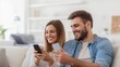 © mirifadapt - smiling couple sitting on sofa, man holding smartphone in his hands