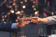 © Kritdanai - Cheers to Success: Two hands clink glasses of amber liquid in a toast, capturing the celebratory spirit of a successful event or partnership.