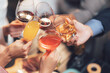 © Kritdanai - Cheers to Success: A close-up shot of hands clinking glasses filled with various beverages - red wine, orange juice, cocktails, and whiskey - symbolizing a toast to achievement, collaboration.