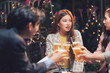 © Kritdanai - Nightlife Cheers: Friends toasting beers at an outdoor patio, enjoying a lively evening.  Warm lighting and casual atmosphere.