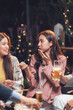© Kritdanai - Night Out Laughter: A group of friends enjoys a lively conversation over drinks at a dimly lit outdoor bar.  The image captures the warmth and conviviality of a social gathering.