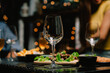 © Kritdanai - Nighttime Dinner Gathering: A captivating close-up of an empty wine glass at the center of a table laden with delicious food, surrounded by friends enjoying a festive evening under warm.