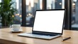 © crispy - Laptop with blank screen on wooden desk in city office. Coffee cup and pen nearby. Urban view through window. Remote work setup with copy space for design or text