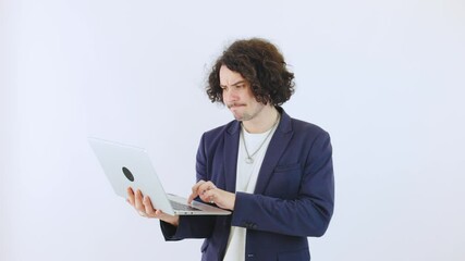 A young sad curly-haired programmer in a blazer is typing on a laptop against a white isolated background, focusing on his work